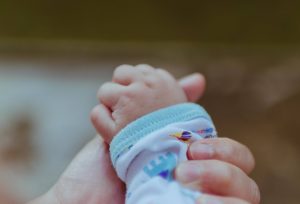 holding the hand of a baby with silent reflux
